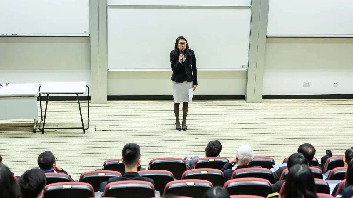 Female speaker presenting to an audience in a modern aud