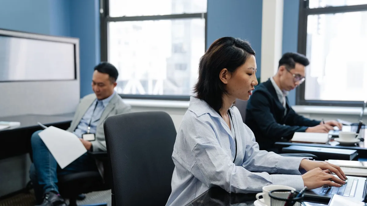 Focused asian professionals working on laptops in a mode
