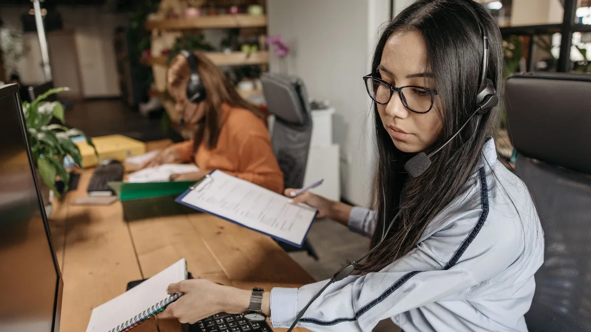 Focused call center agent wearing headset managing paper