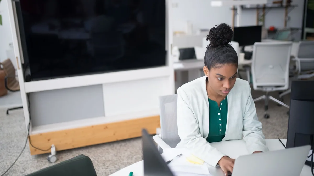 Focused woman using a laptop in a modern office setting