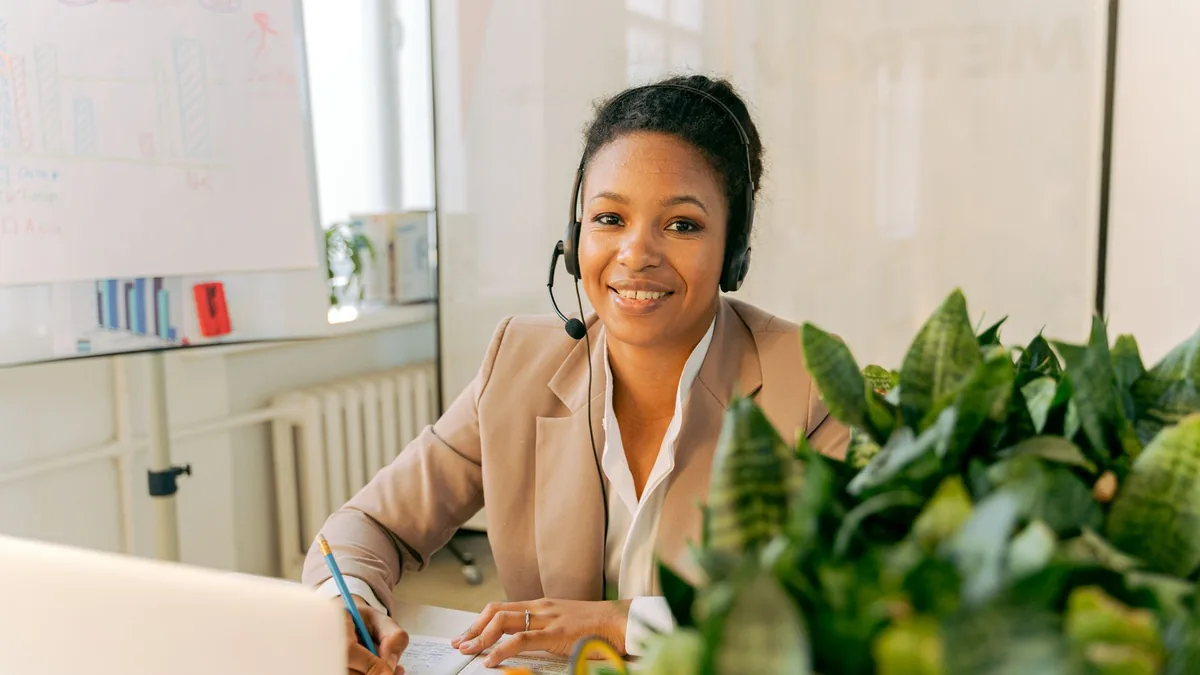 Friendly call center agent smiling at her desk with head