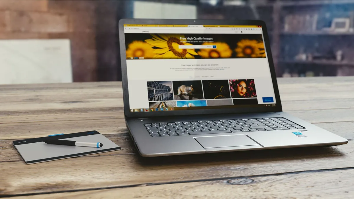 Laptop with open webpage on wooden desk accompanied by t