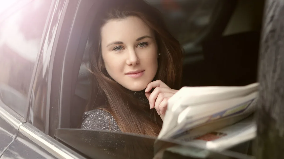 Long haired female with newspaper thoughtfully looking a