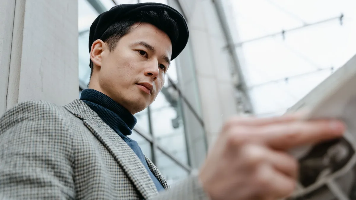 Low angle shot of stylish asian man in gray suit holding