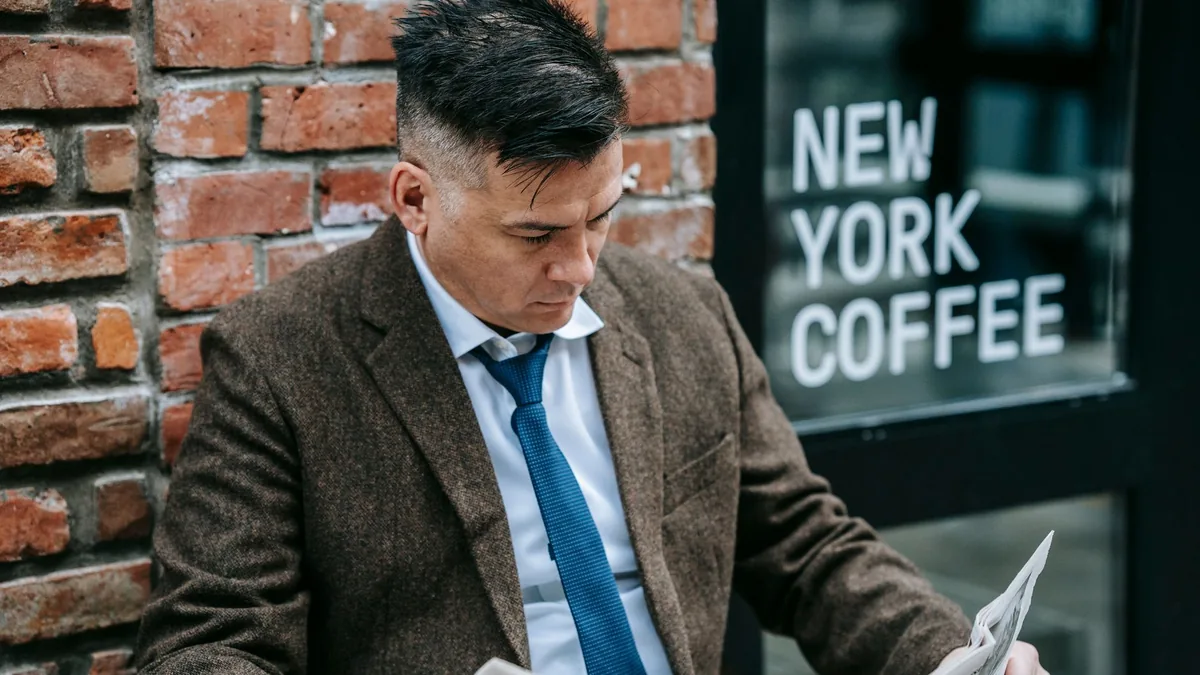 Man in formal attire reading a newspaper outside new yor