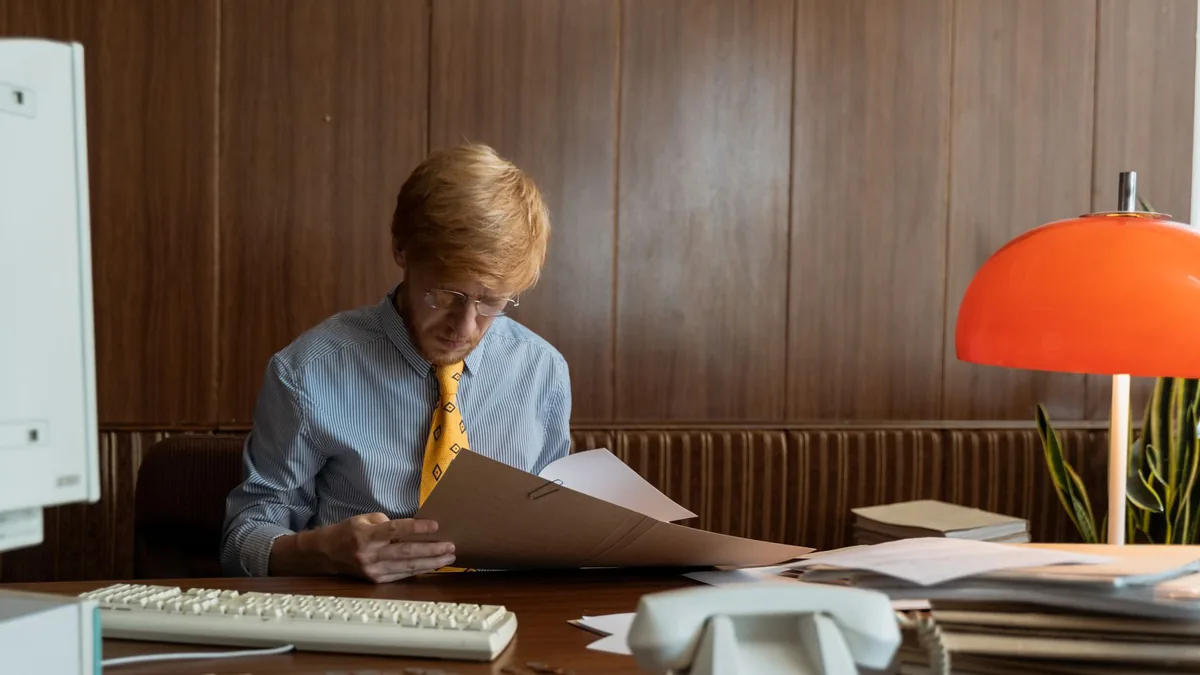 Man in retro office setting reviewing documents under wa