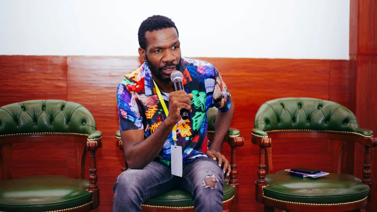 Man in vibrant shirt using a microphone during an indoor