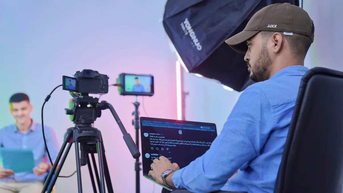 Man operates camera and laptop during a studio video sho
