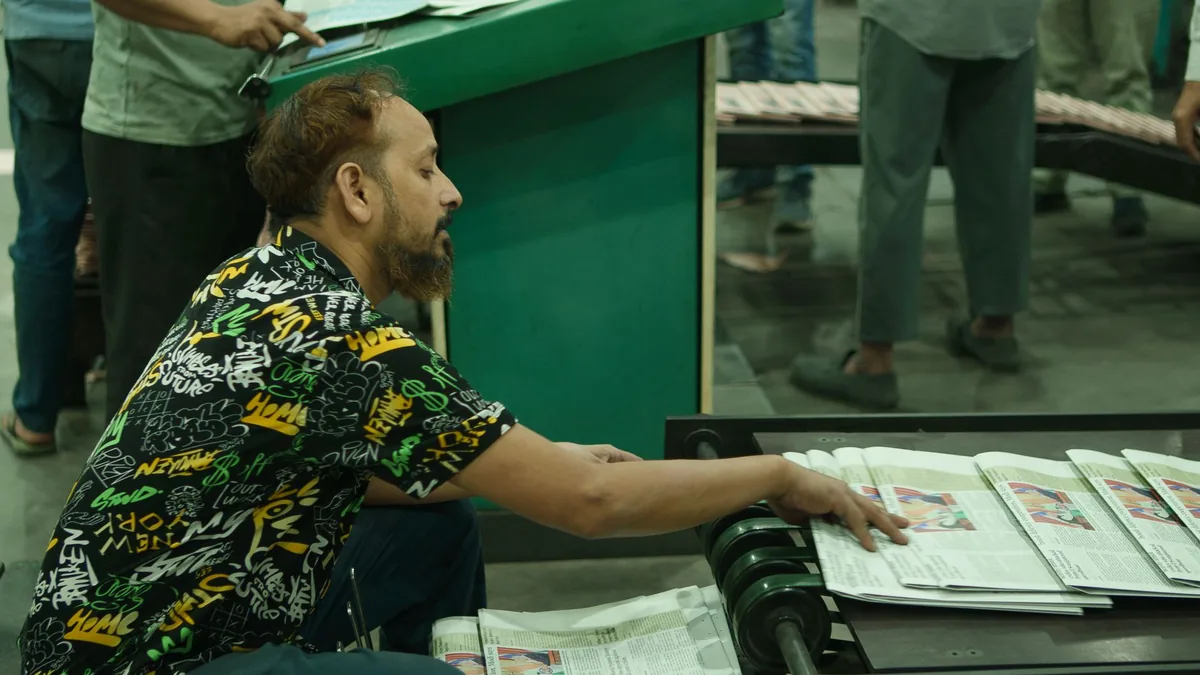 Man sorting newspapers on a conveyor belt in a busy prin