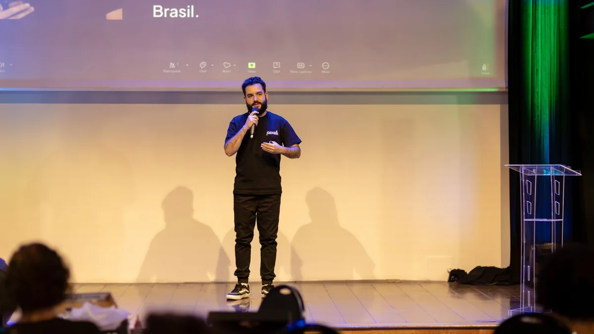 Man speaking on stage with a microphone at a conference