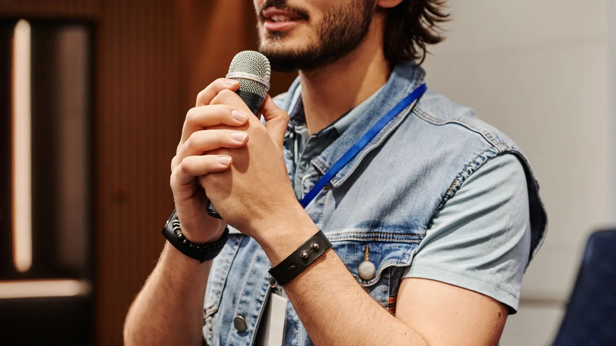 Man with a beard speaks into a microphone during an indo