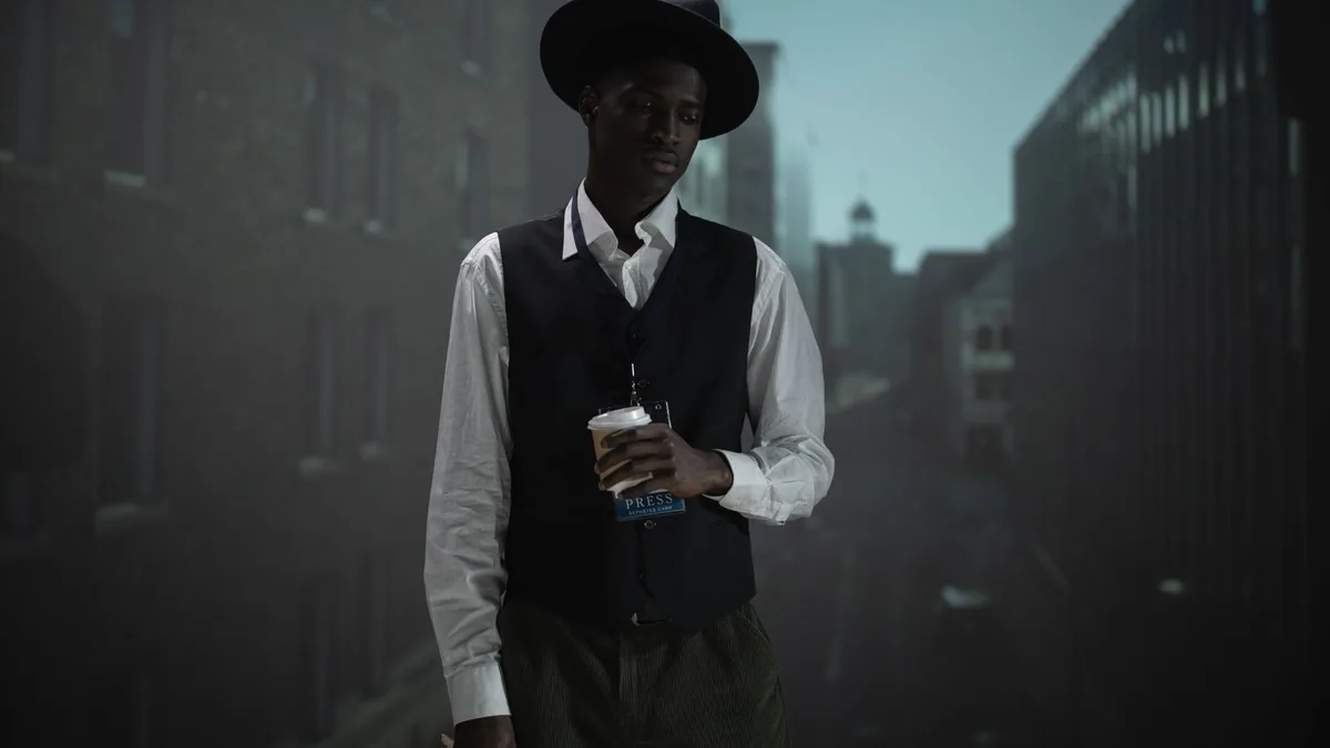 Man with coffee wearing a vest and fedora set against an