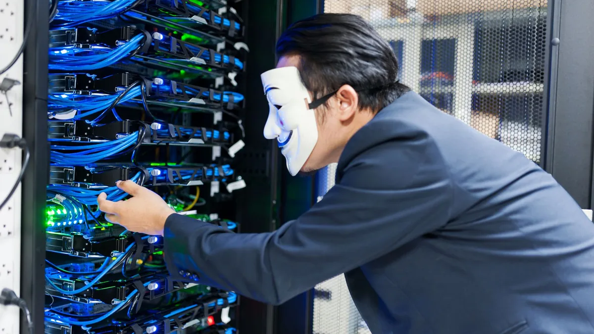Masked individual interacting with server racks symboliz