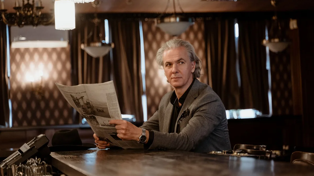 Mature man in a stylish suit reads a newspaper at an ele