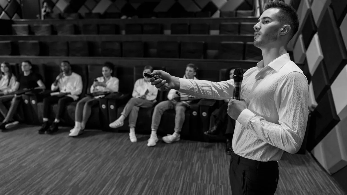 Monochromatic image of a speaker presenting to a small a