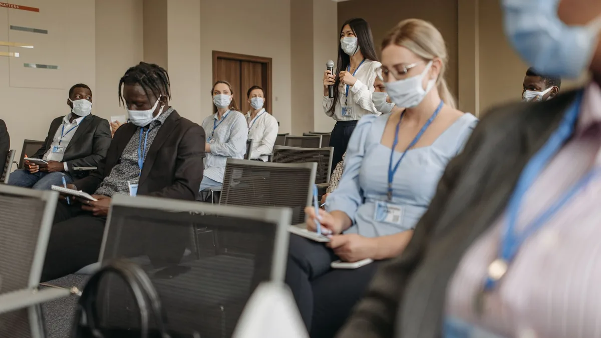 Participants wearing masks engage in a business seminar
