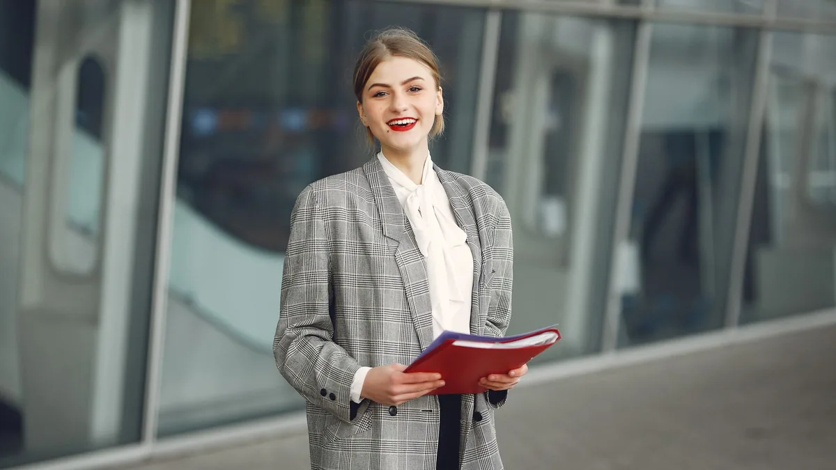 Positive young woman in trendy wear smiling at camera wh