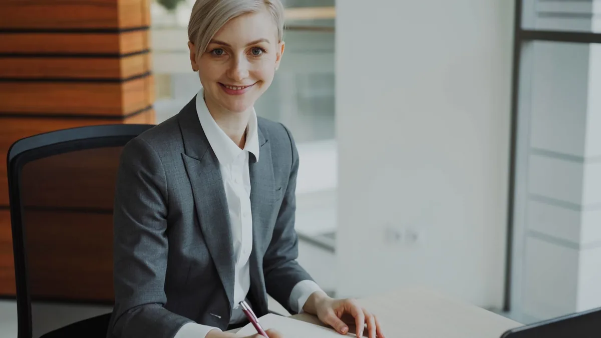 Professional businesswoman smiling at desk in modern off