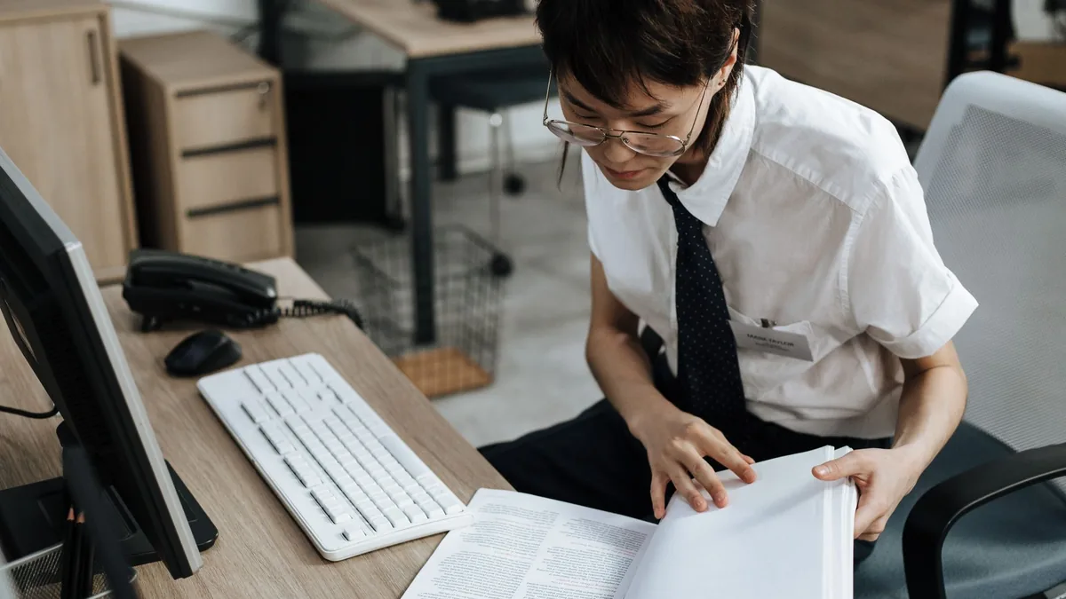 Professional in office attire reviewing documents at a d