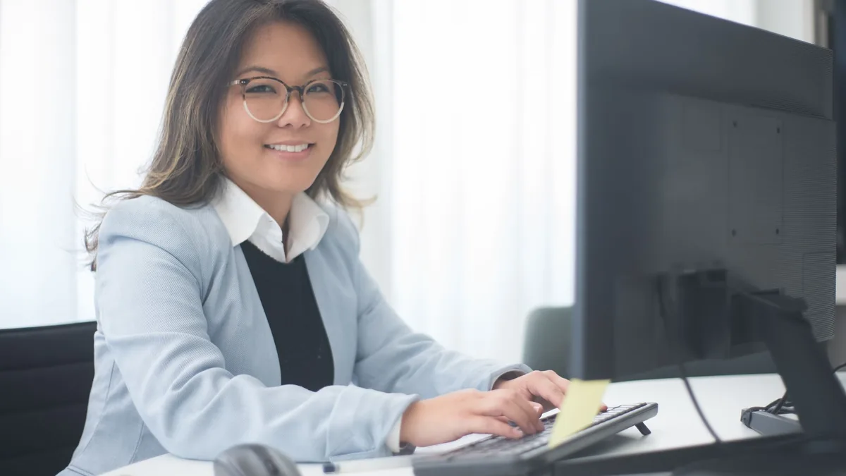 Professional woman smiling while working at a computer i