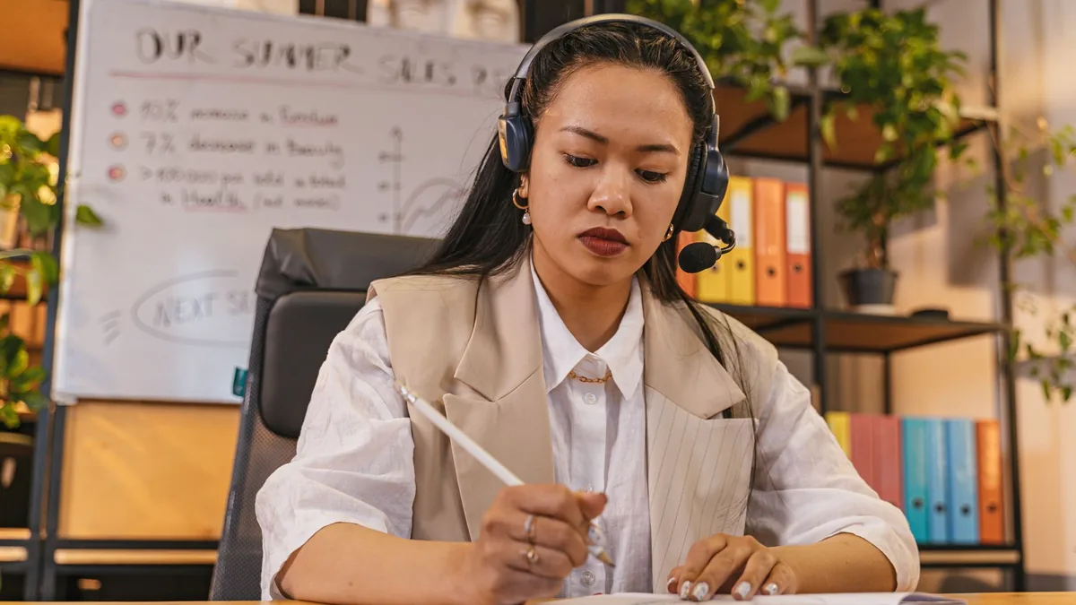 Professional woman wearing a headset taking notes in an