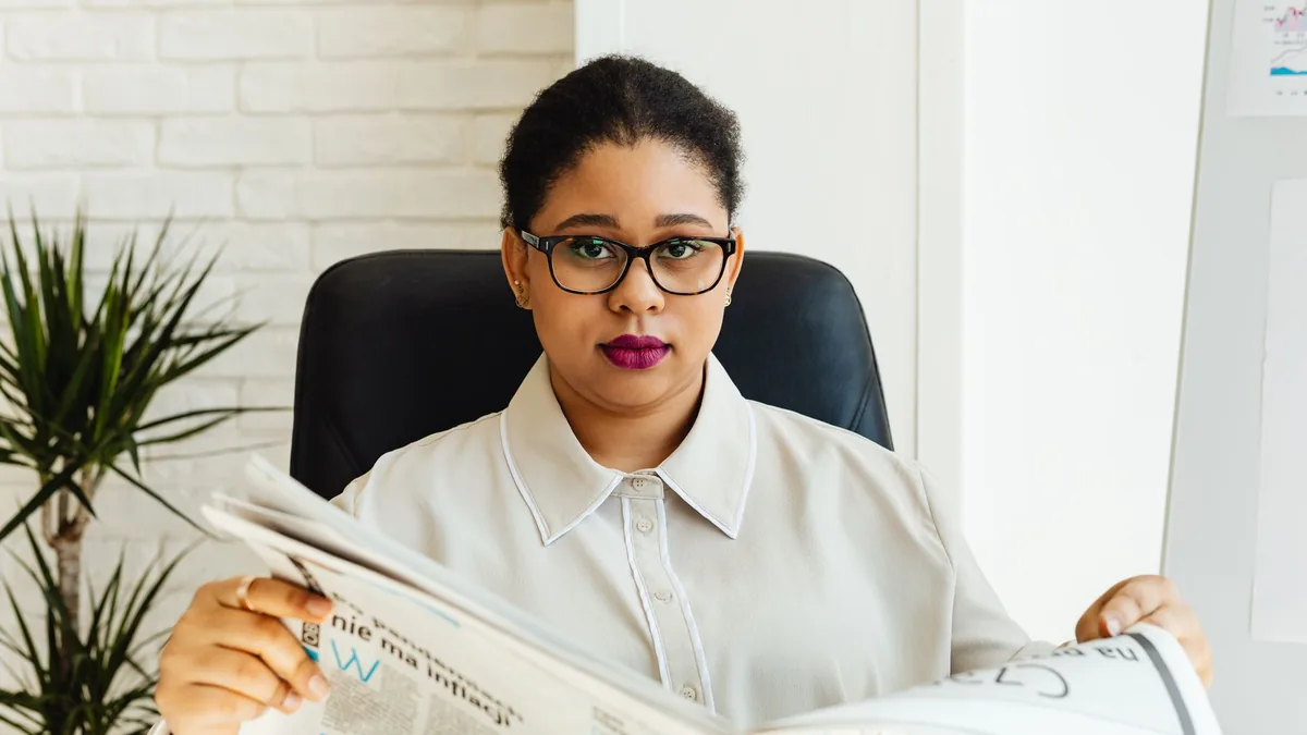 Professional woman with glasses reading a newspaper at h