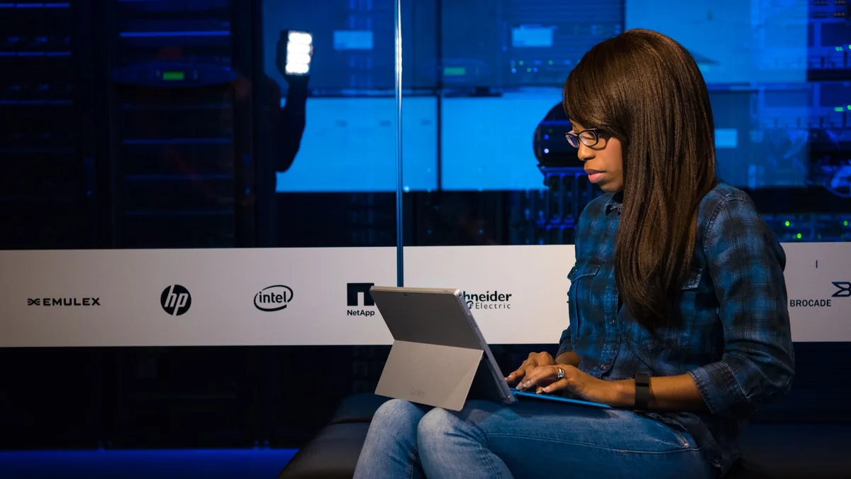 Professional woman working on laptop in a server room sh