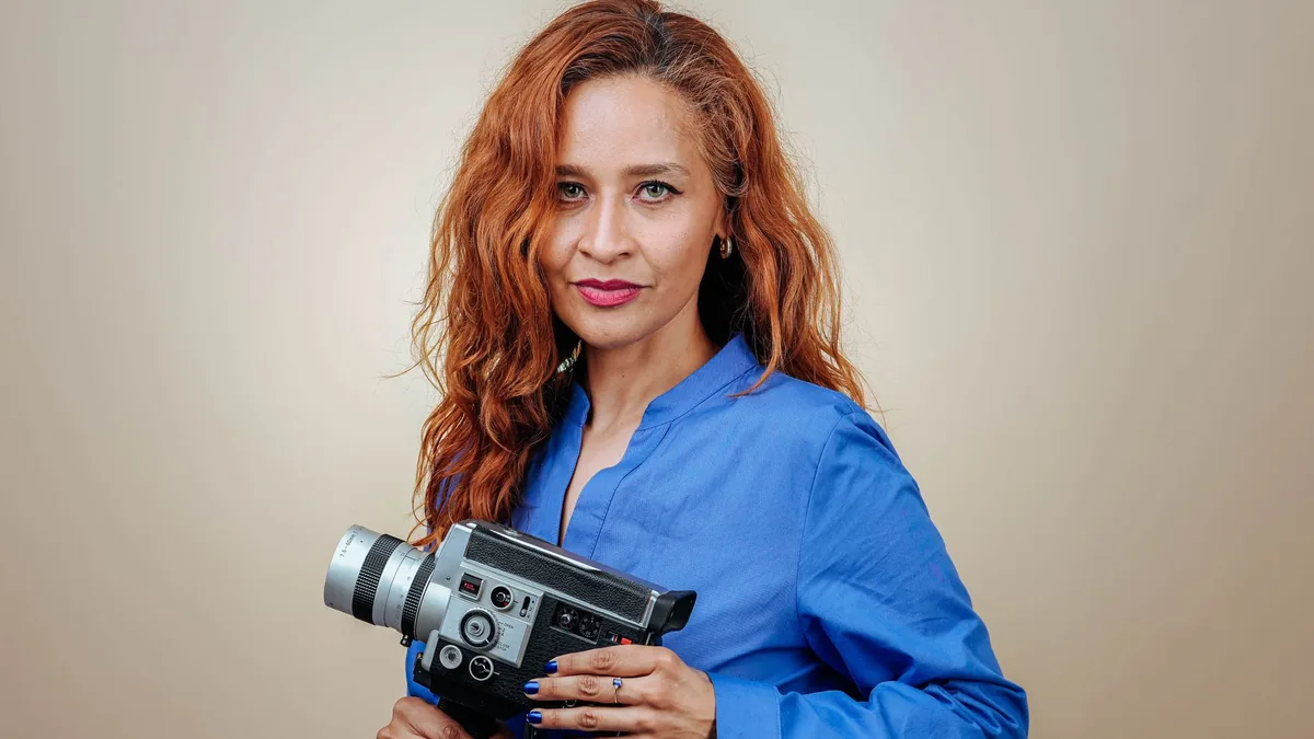 Redhead woman in blue shirt holding a vintage camera in