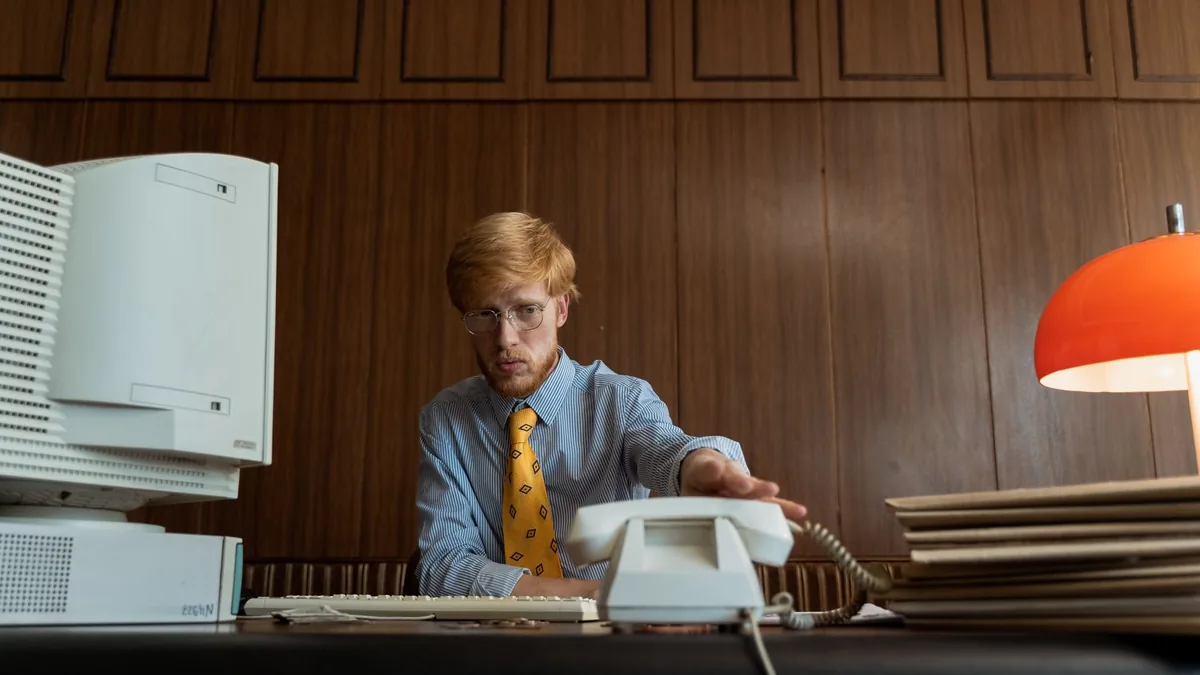 Retro office setup featuring a man with a vintage comput