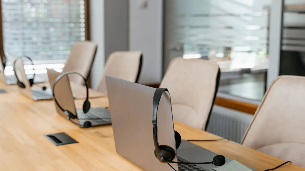Row of laptops with headsets in a modern office environm