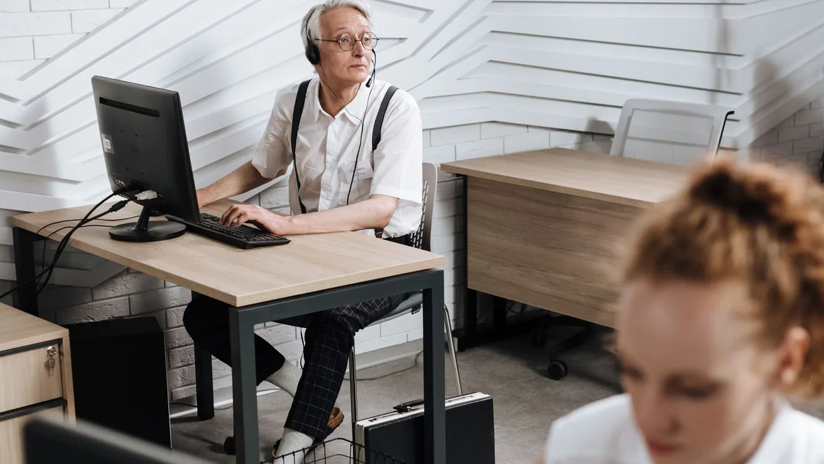 Senior call center agent using a headset and computer in