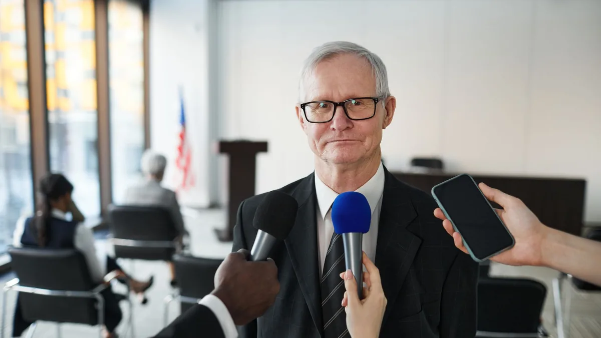 Senior man in formal attire being interviewed in a confe