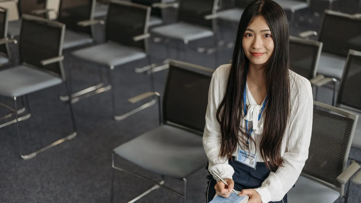 Smiling asian woman with notebook sitting in an empty co