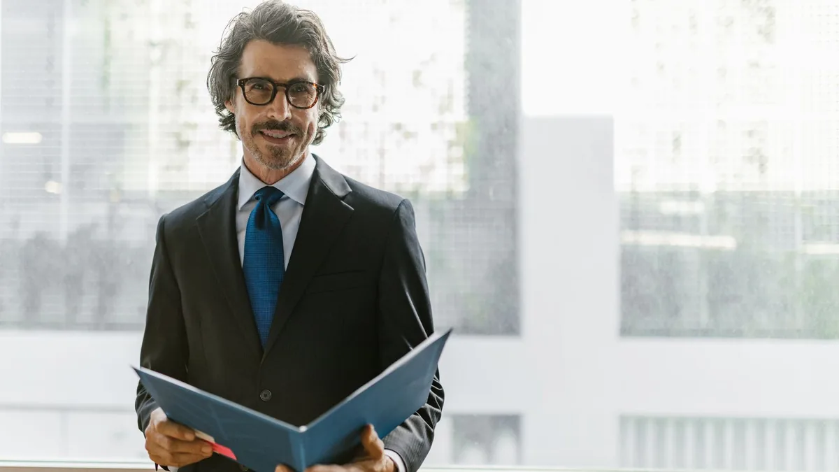Smiling businessman in a black suit holding a blue portf