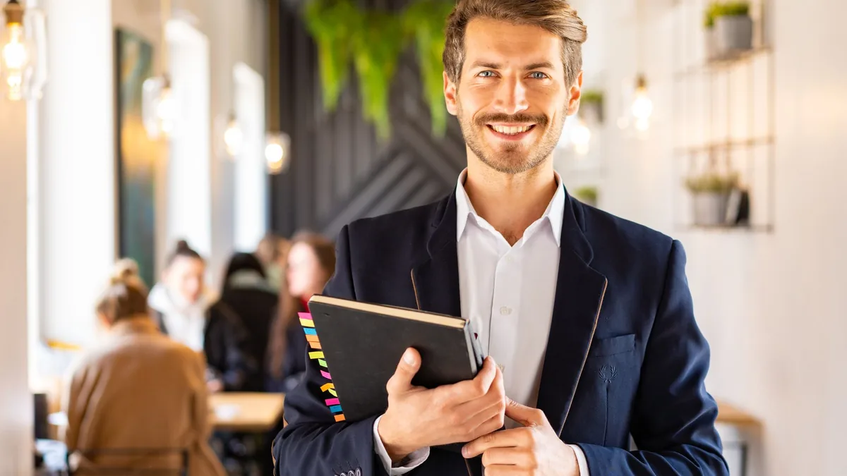 Smiling businessman in a blue suit holding a notebook in