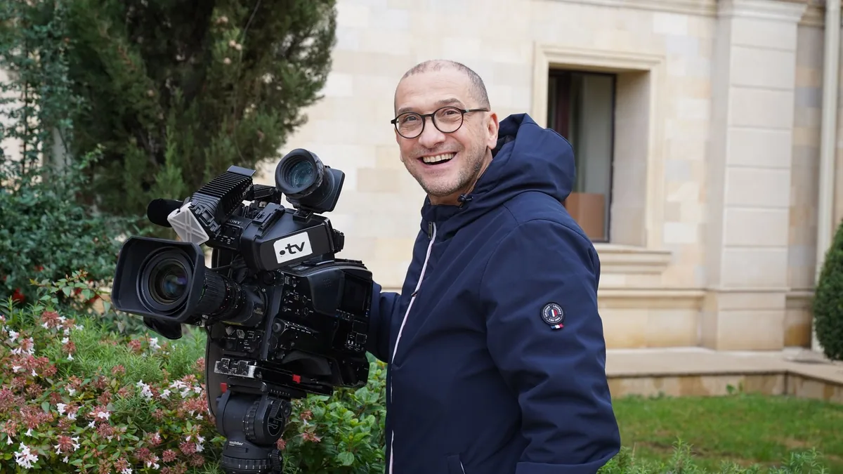 Smiling cameraman with a large tv camera in an outdoor s
