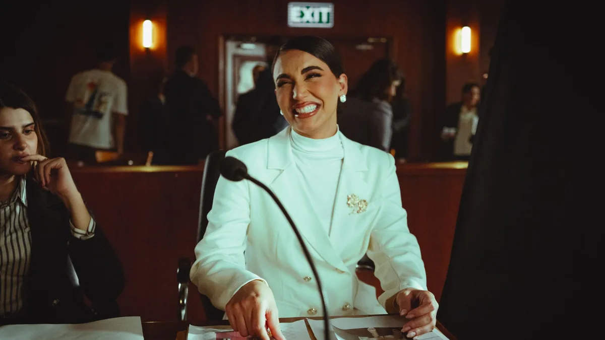 Smiling woman in white suit in a courtroom conveying pro