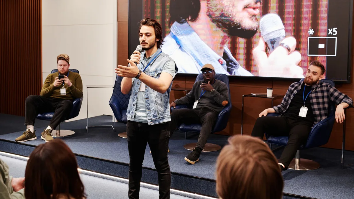 Speaker holds microphone engaging audience at an indoor
