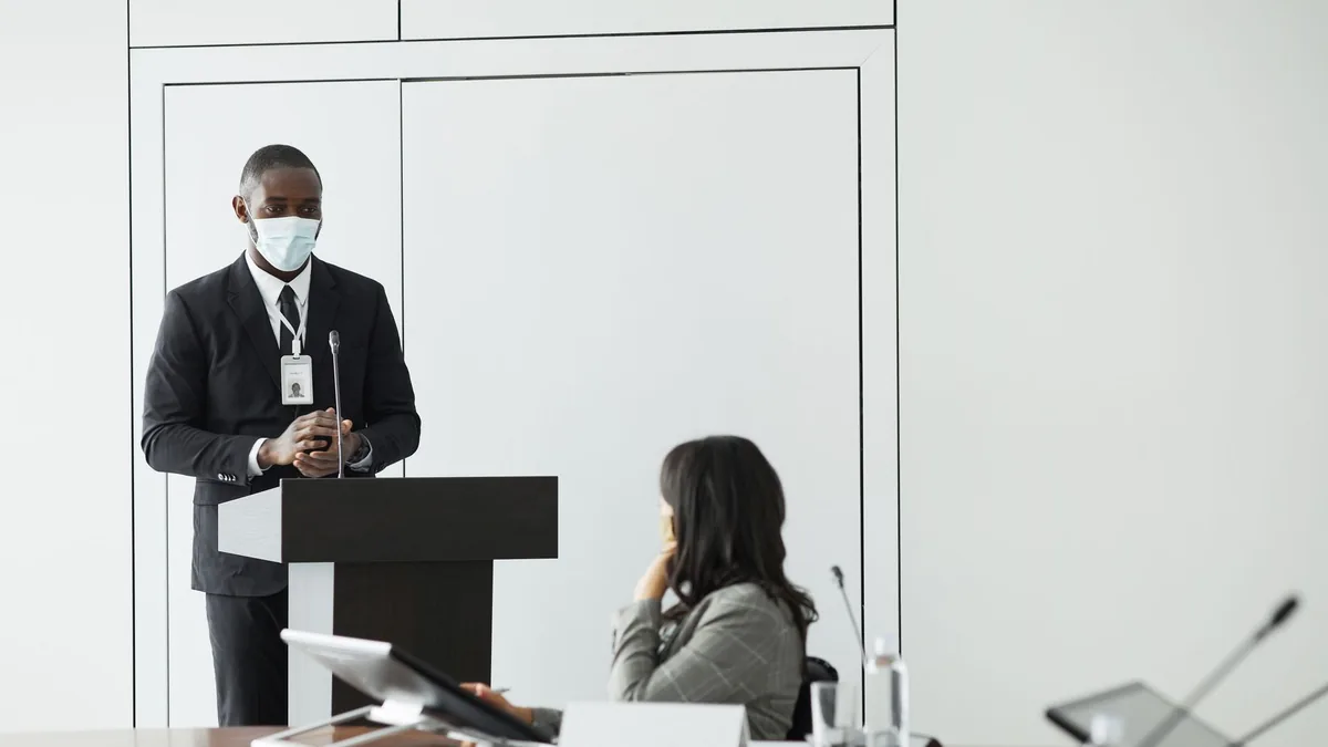 Speaker in mask presenting during a business conference