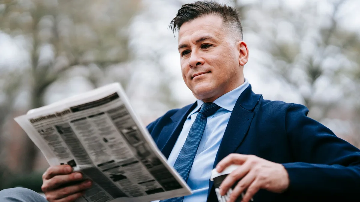 Stylish man in formal wear enjoys a drink while reading
