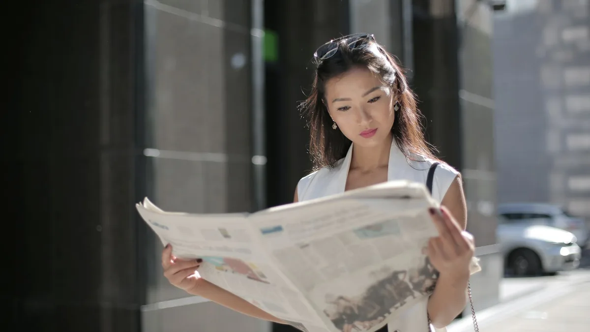 Stylish woman reading a newspaper on a sunny day in the