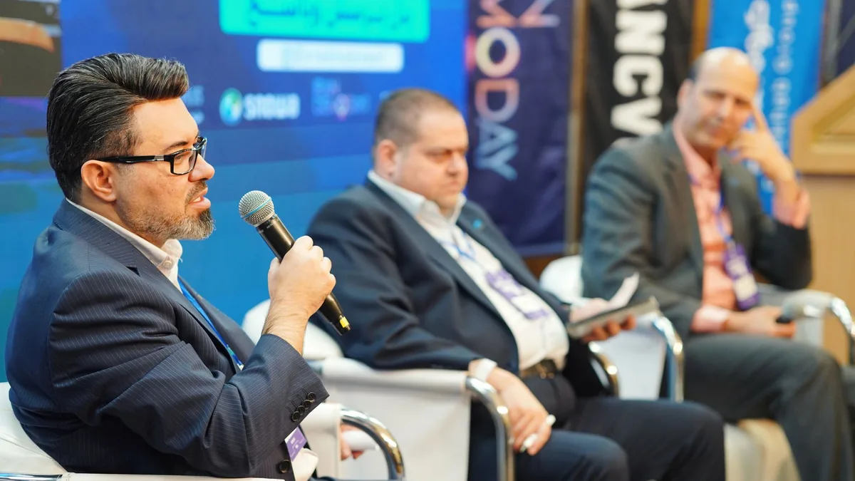 Three men engaged in a panel discussion at a professiona