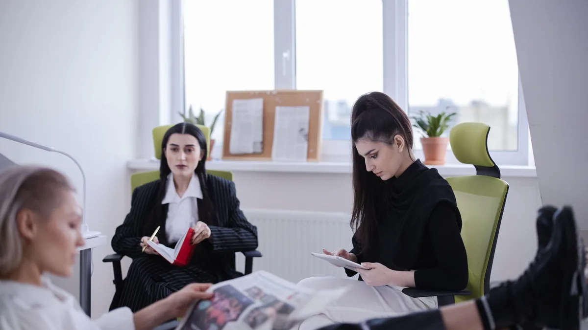 Three women in a modern office setting reading and worki