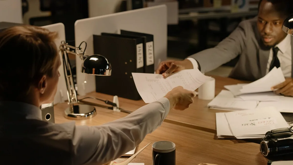 Two business professionals exchanging documents in a col