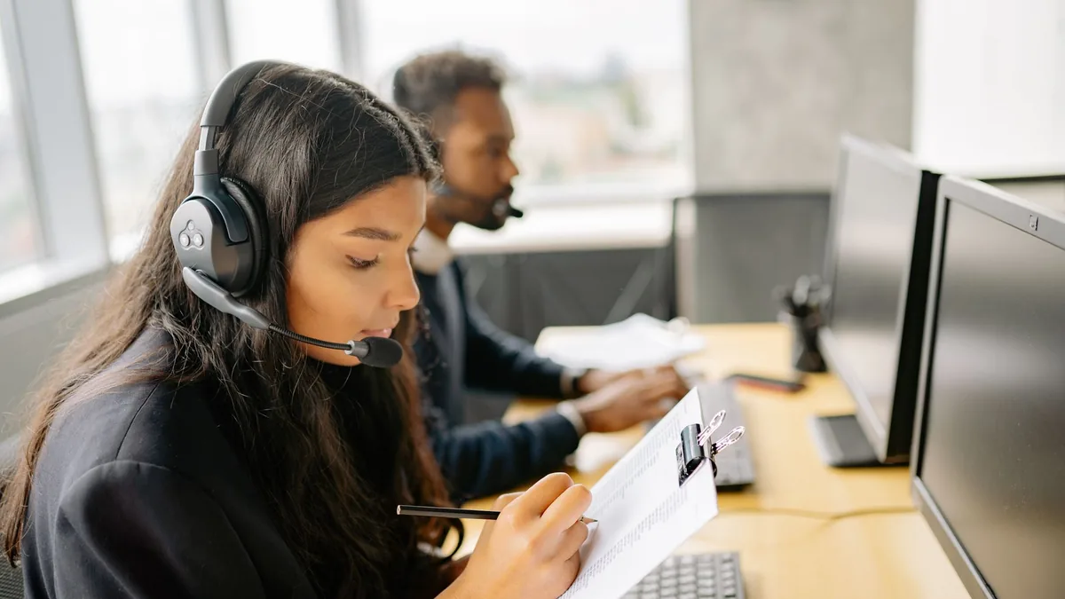 Two call center agents wearing headsets working at desks