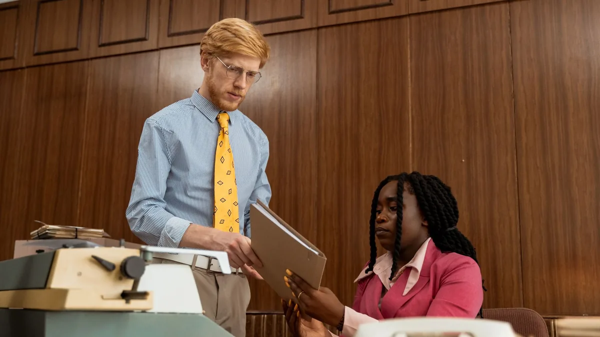 Two colleagues collaborate with vintage office equipment