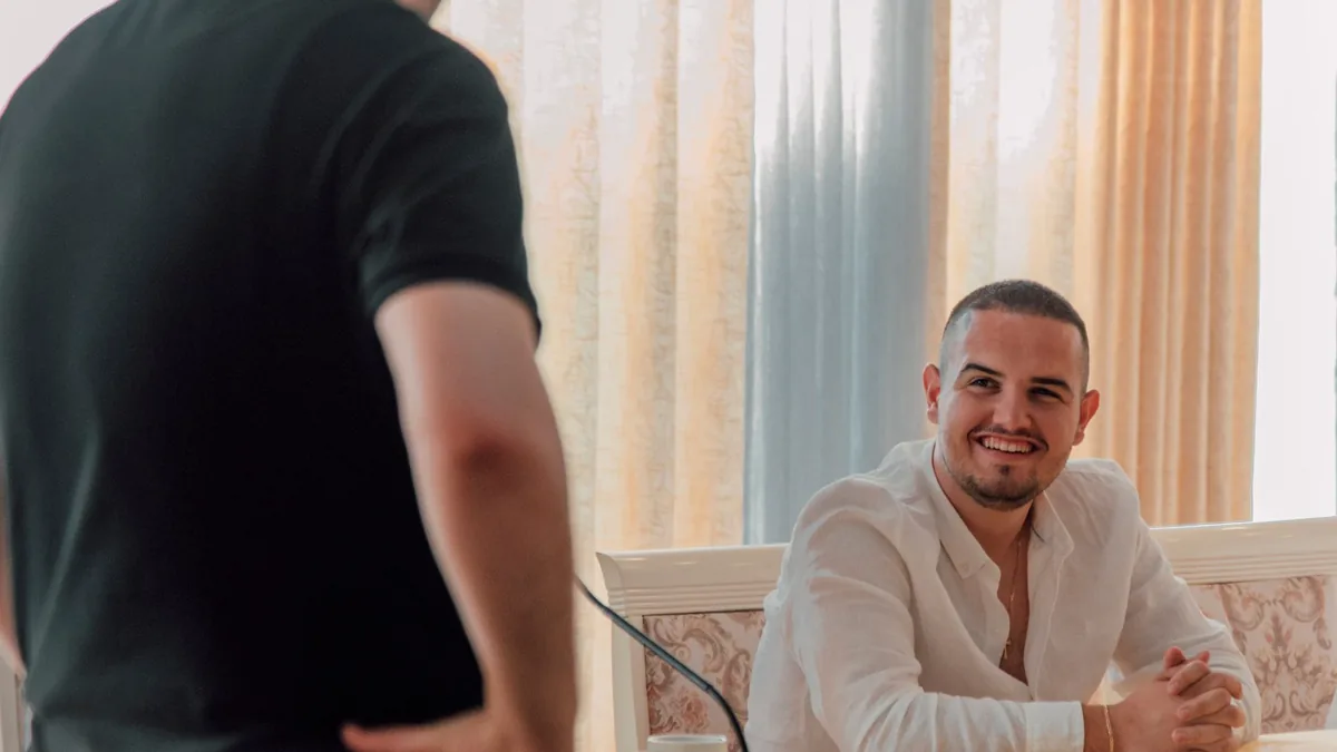 Two men in a casual business meeting setting one is smil