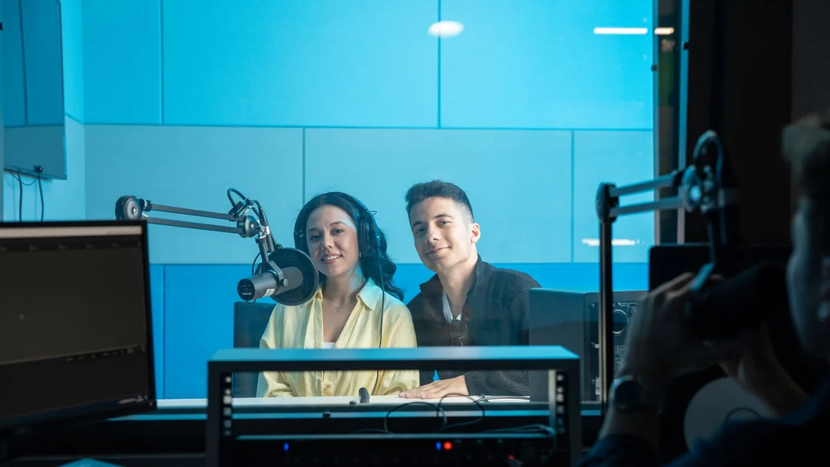 Two people in a radio studio broadcasting a show featuri