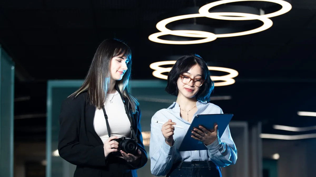 Two professional women discussing work on a tablet and c