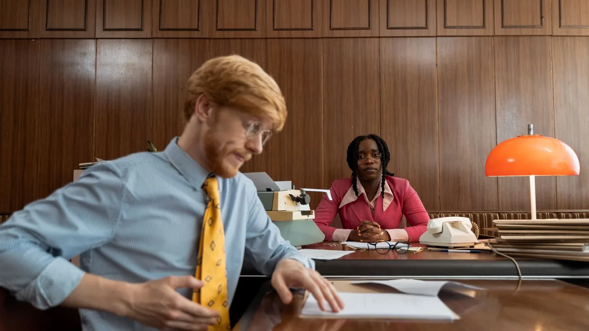 Two professionals engaged in a serious office meeting wi